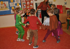 Grupka dzieci tańczy wesoło w małym kółeczku. Razem z dziećmi tańczy nauczycielka. Ujęcie 3